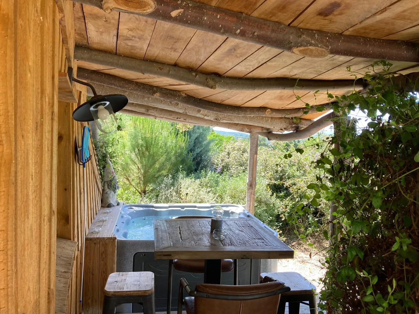Le jacuzzi privatif est situé sous la terrasse abritée de la maison Hobbit